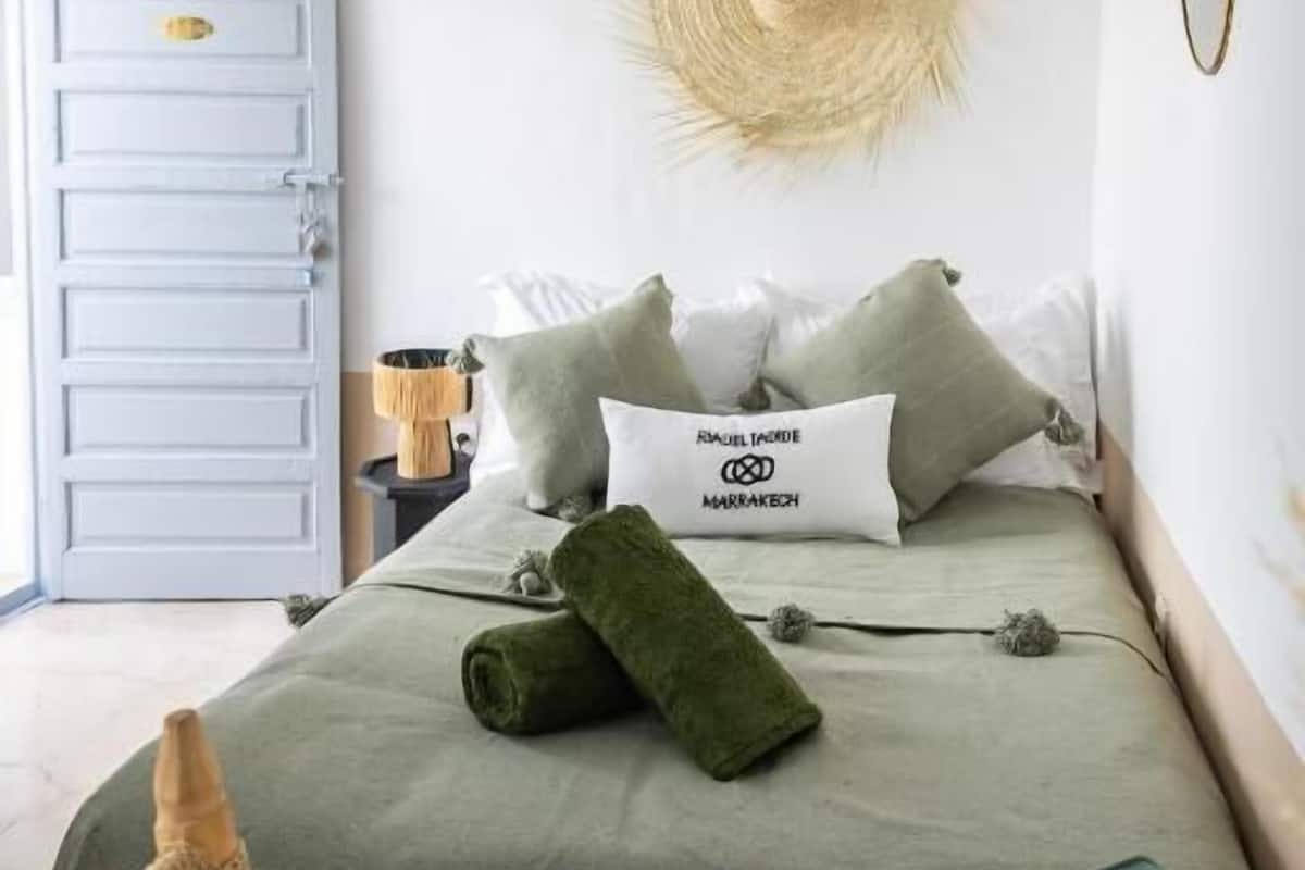 A neatly arranged bedroom with a bed, a bedside table, a hanging basket, and a door.