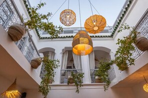A courtyard with hanging wicker lamps, white walls, and potted plants. - Riad El Jadide (Marrakech)