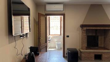 Ein Zimmer mit flachbildfernseher an der Wand, Kamin, Fenster mit Blick und Fliesenboden.