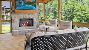 A cozy living room with a stone fireplace, comfortable seating, and a large window offering a scenic view.