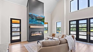 A modern living room with a fireplace, a large flat-screen TV, and a cozy seating area.