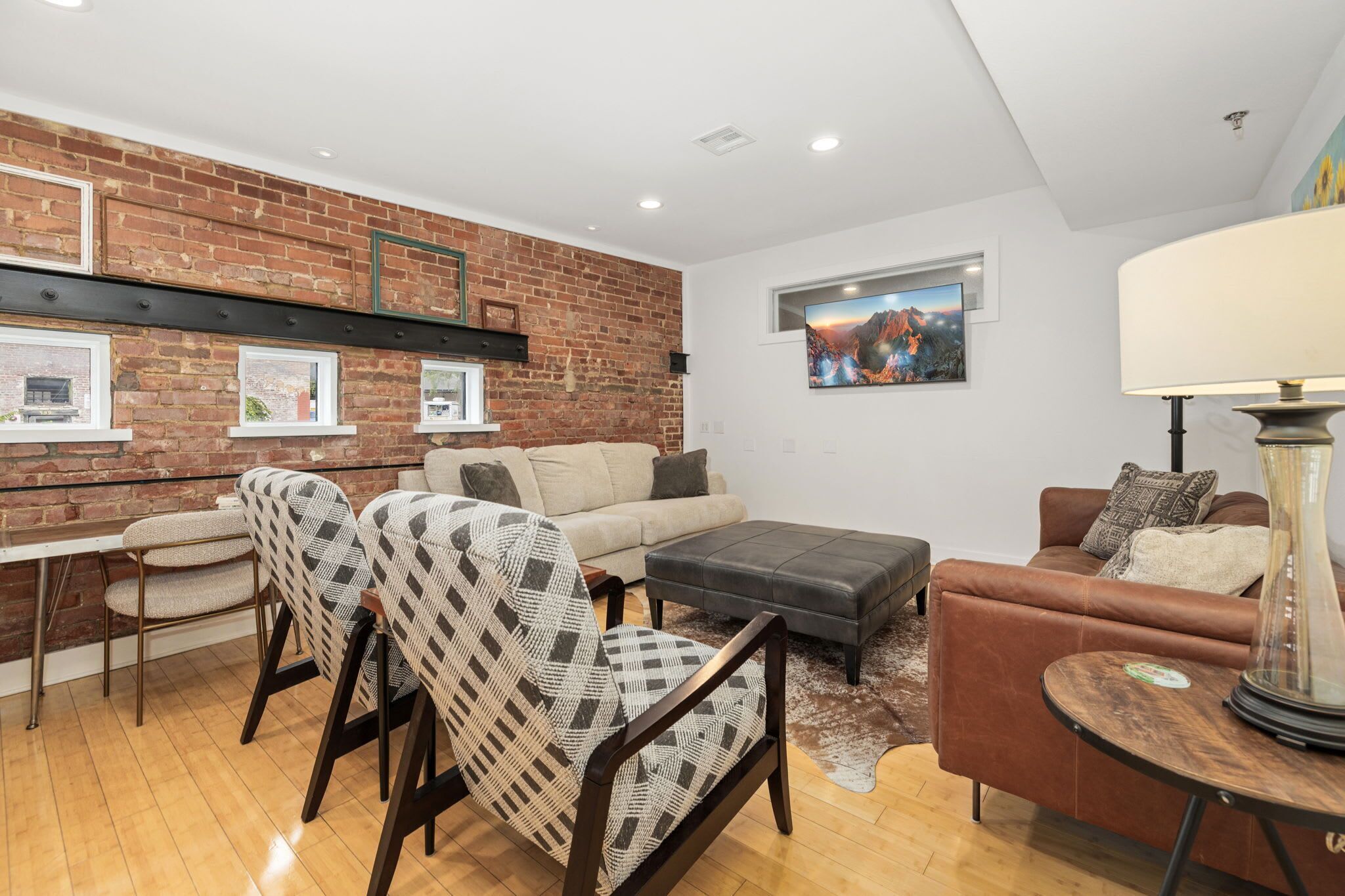 A living room with a brick wall, a sofa, a loveseat, a coffee table, and a TV.