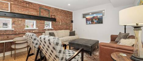 A living room with a brick wall, a sofa, a loveseat, a coffee table, and a TV.