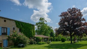 A house with a garden, a tree, and a small structure.