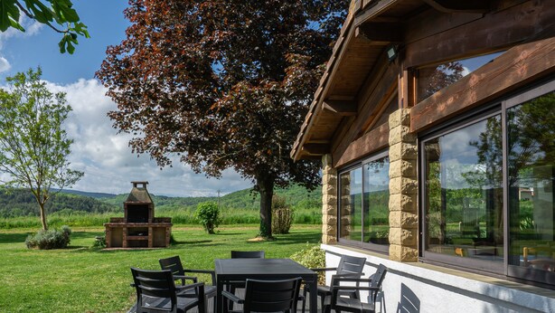 A patio with a table and chairs, a stone fireplace, and a view of the surrounding landscape.