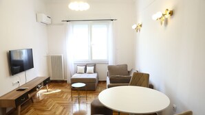 A modern living room with a sofa, a round table, and a TV.
