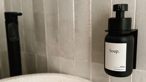 Un dispensador de jabón negro con una etiqueta que dice "Jabón. 250 ml con cariño desde Hamburgo.".