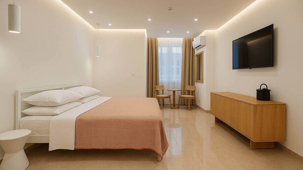 Una habitación de hotel moderna con una cama, una mesita de noche y un televisor montado en la pared.