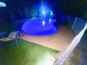 Una piscina amb una zona de sorra i un tram enjardinat.