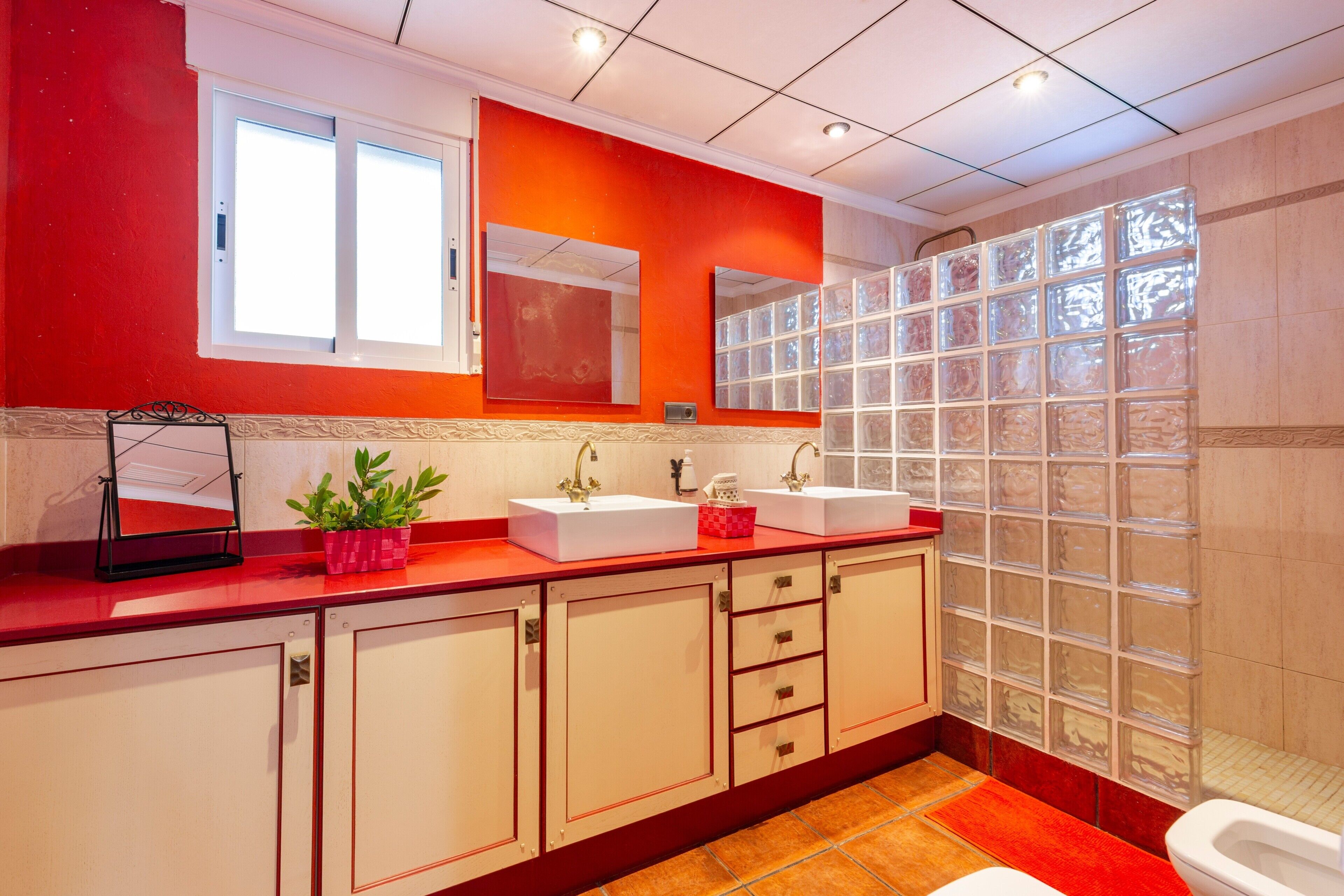 Un bagno con due lavandini, uno specchio, una finestra e un muro in vetro blocchi.
