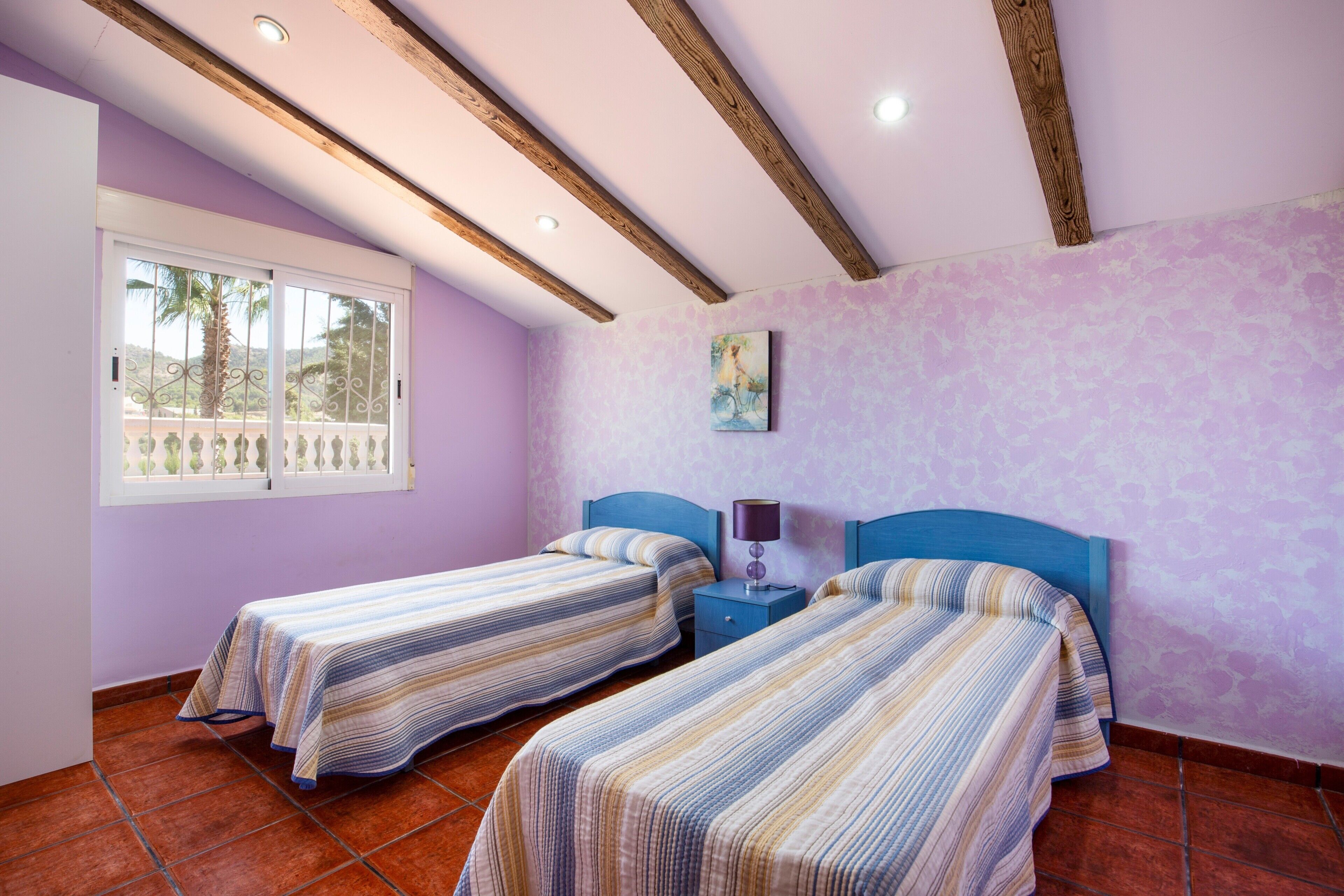 Un dormitorio con dos camas, una ventana con vistas y un techo con vigas de madera.