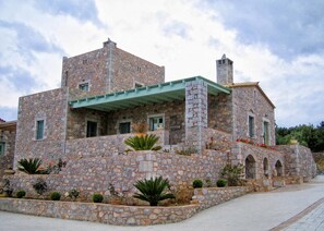 A stone building with multiple levels, a green roof, and a courtyard with plants.