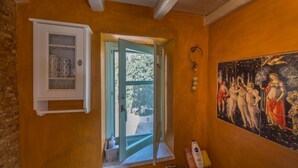 A bathroom with a window, a cabinet with glass doors, and a painting on the wall.