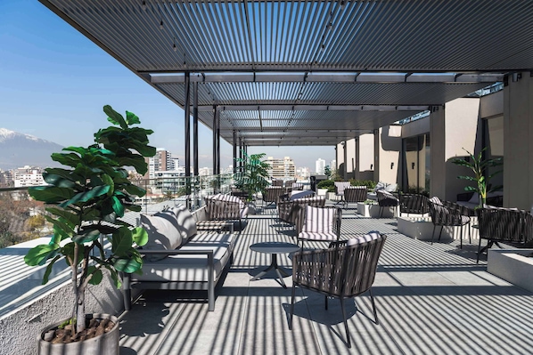 A rooftop terrace with outdoor seating, potted plants, and a view of the cityscape.