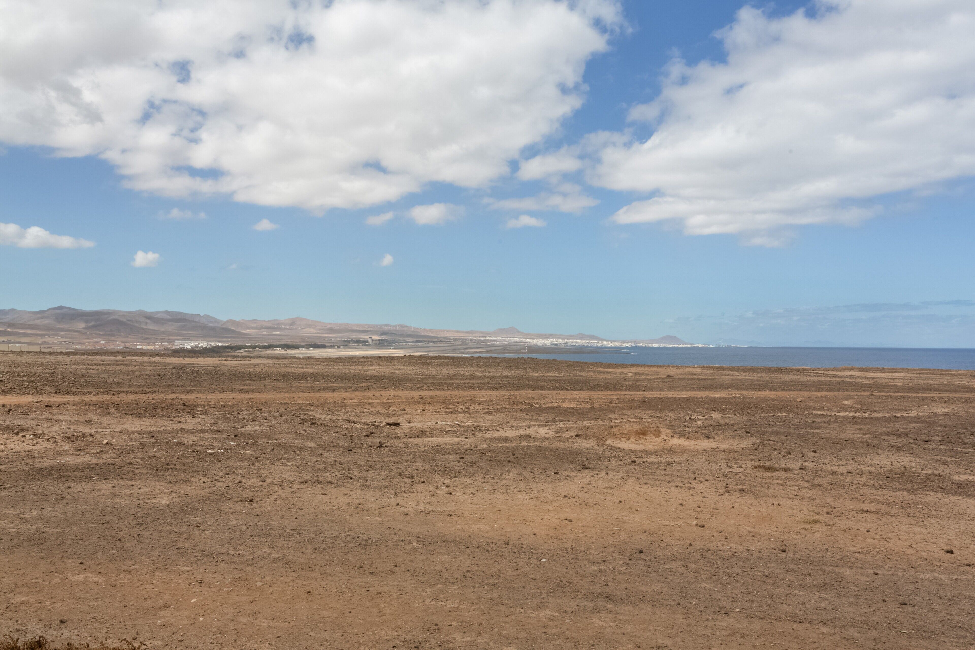 A barren landscape with distant mountains and a clear sky.