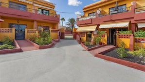 A hotel with a central courtyard, balconies, and a clear sky. - Vacation Apartment 'Casa Lita' with Shared Pool, Private Terrace, and Wi-Fi (Antigua)