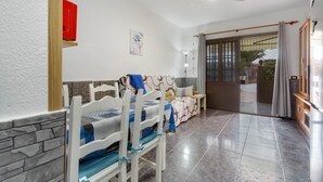 A room with a bed, a sofa, a dining table with chairs, a ceiling fan, and a view through a glass door. - Vacation Apartment 'Casa Lita' with Shared Pool, Private Terrace, and Wi-Fi (Antigua)