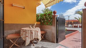 An outdoor patio with a table and chairs, a refrigerator, and a decorative wall with flowers. - Vacation Apartment 'Casa Lita' with Shared Pool, Private Terrace, and Wi-Fi (Antigua)