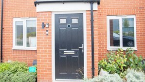 A brick house with a black front door, two windows, and a small garden area.