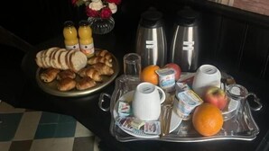 A breakfast tray with croissants, orange juice, and a fruit bowl on a checkered floor. - Imperial Suite & Spa (Béthune)