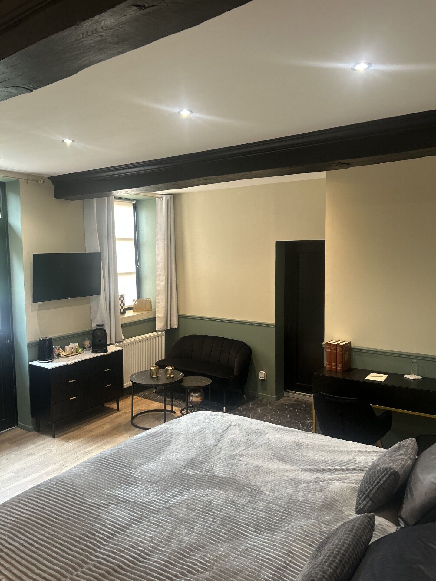 A hotel room with a bed, a desk, a chair, a TV, and a window with curtains.