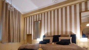 A bedroom with a large bed, a bedside table with a bottle, and a mirror on the wall. - Imperial Suite & Spa (Béthune)