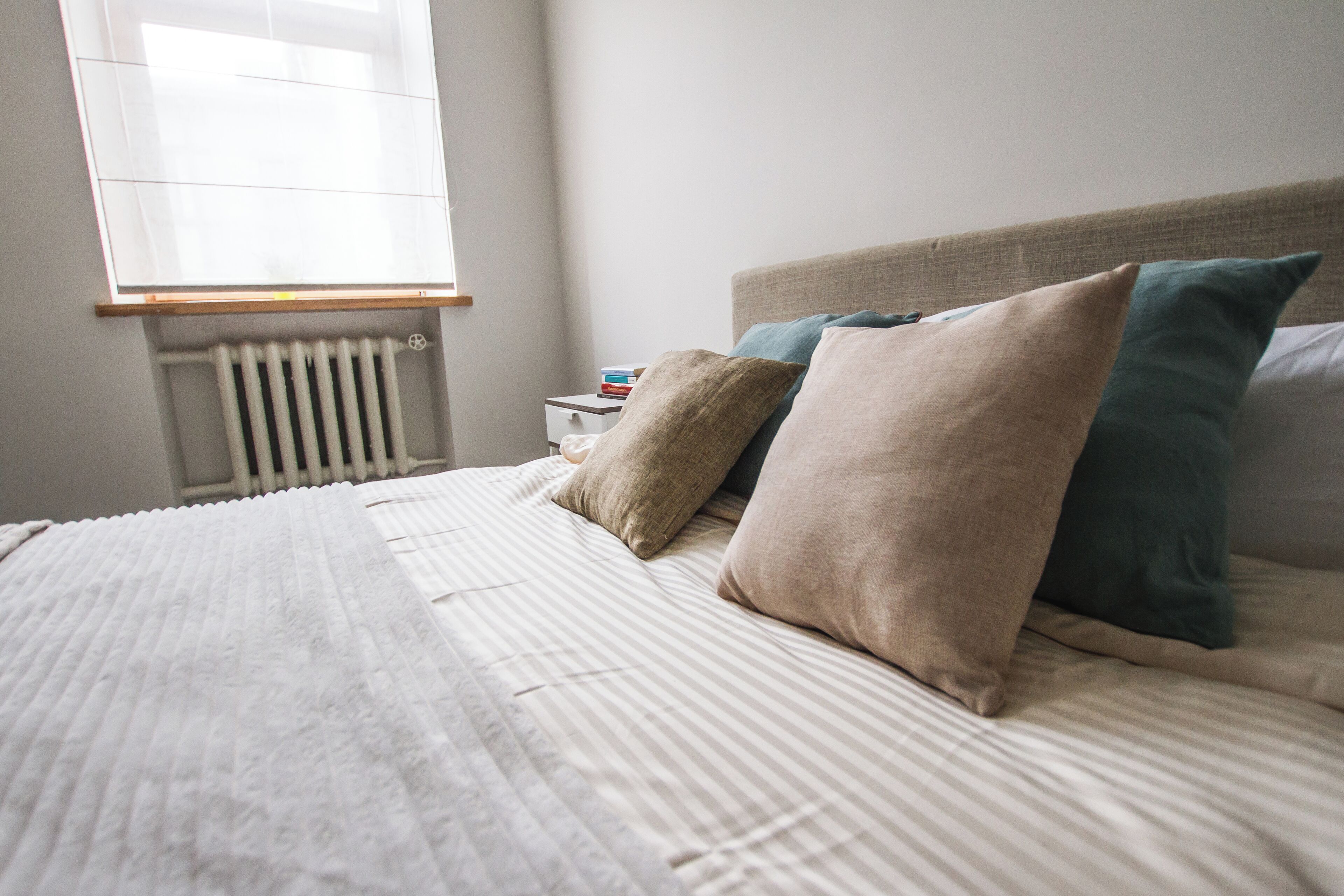Una cama bien hecha con ropa de cama a rayas y varias almohadas.