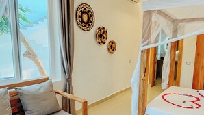 Een slaapkamer met een bed, een slaapbank, een klein tafeltje en een plafondventilator.