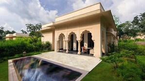 A traditional building with a pool, surrounded by greenery.