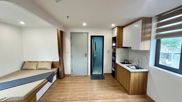 Una habitación compacta con cama, una kitchenette pequeña y un baño.