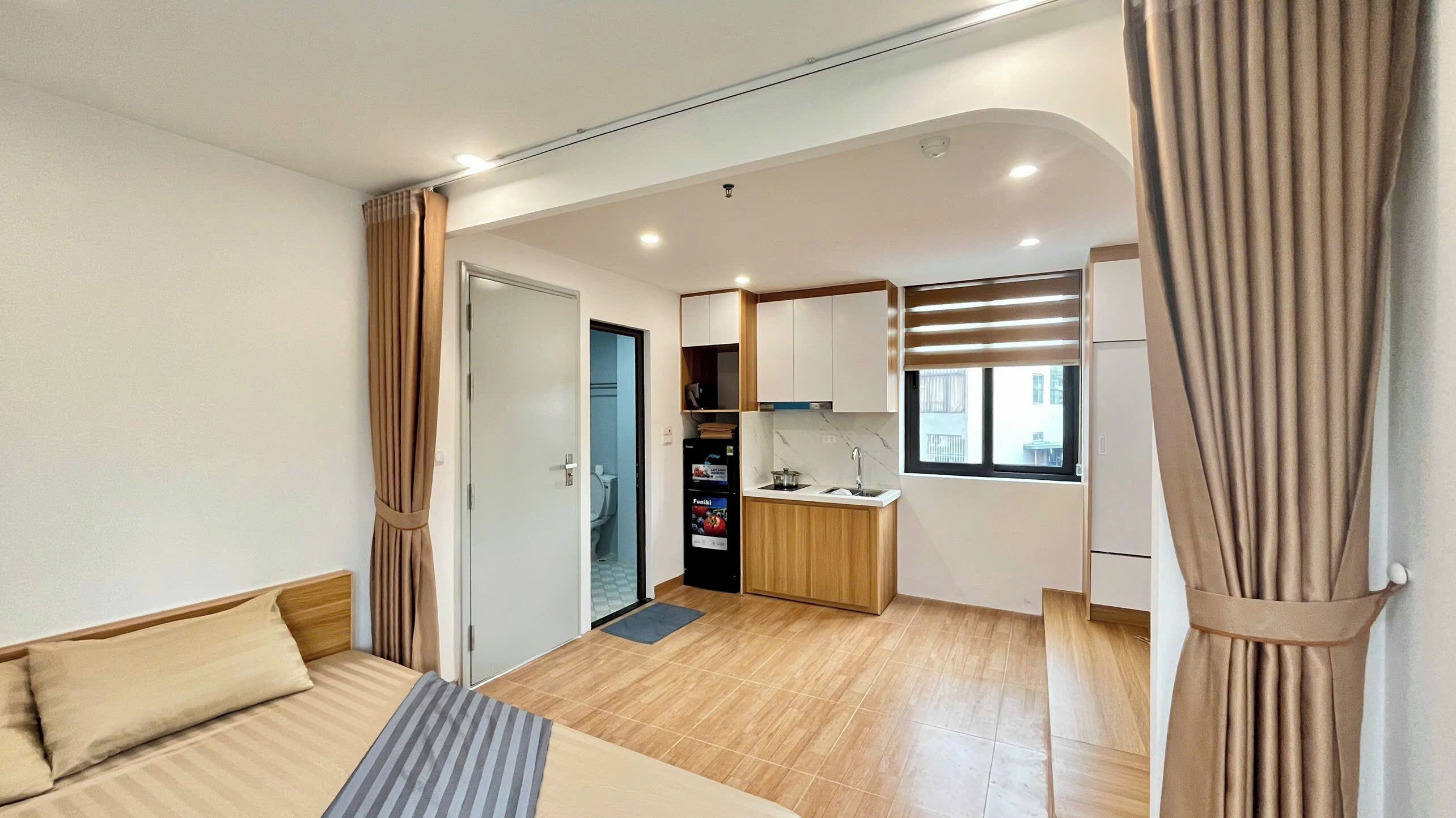 Un espace de vie compact comprenant un coin cuisine, un lit et une salle de bain.