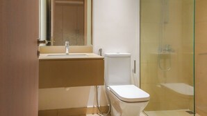 Un baño con inodoro, lavabo y ducha con mampara de vidrio.