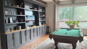 A room with a pool table, dark wood cabinets, and a large window with a view of trees. - Lakefront home in Radford with private dock, large deck, and great views (Radford)