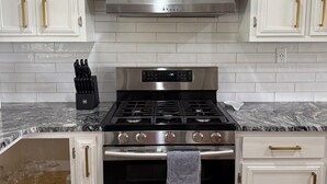A kitchen with white cabinetry, a stainless steel range hood, a gas stove, and a built-in oven. - Lakefront home in Radford with private dock, large deck, and great views (Radford)
