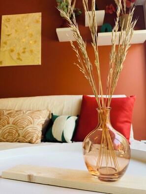 A clear glass vase with dried wheat stalks on a white table.