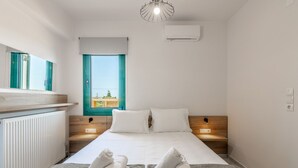 A modern hotel room with a bed, two bedside tables, a window with a view, and a ceiling light. - Sandi Villa (Hersonissos)