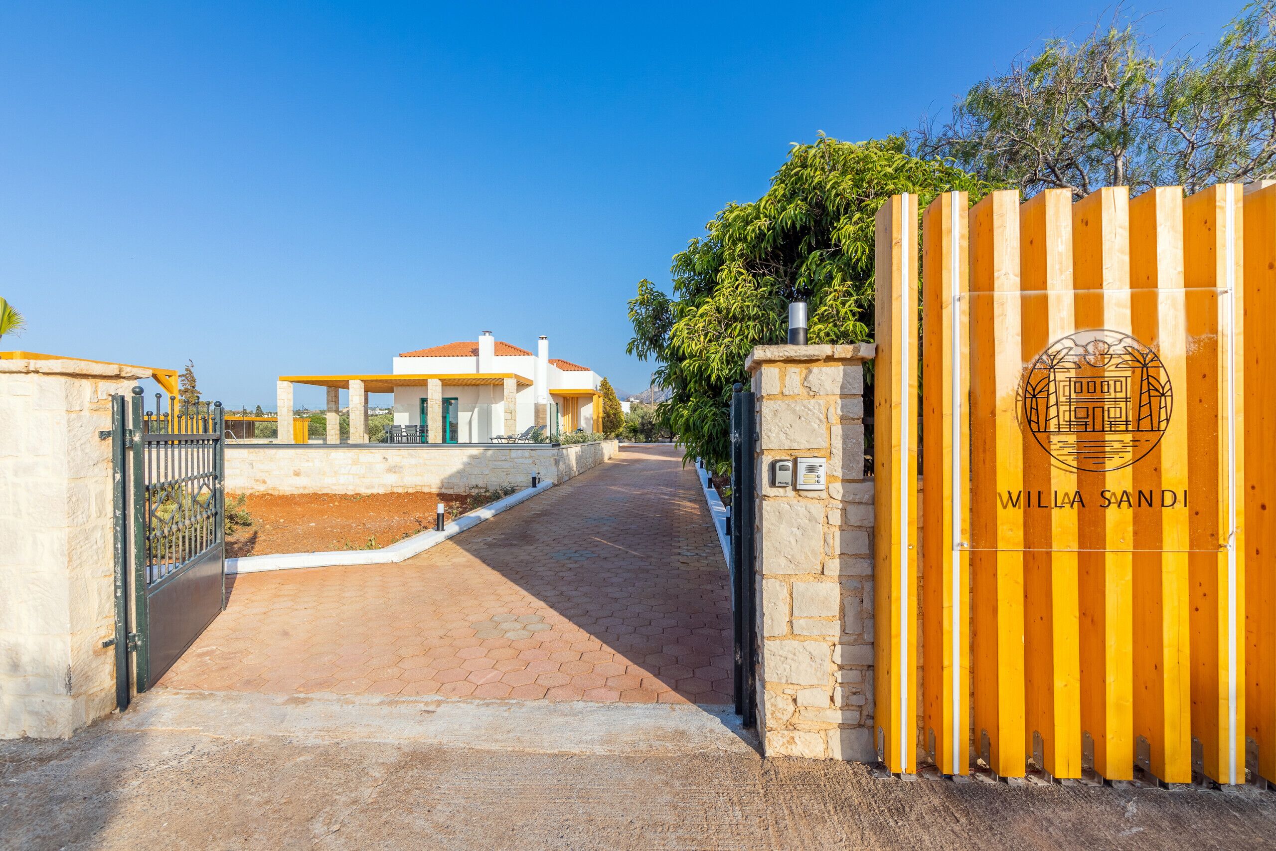 A gated entrance to a property with a clear pathway leading to a building with a red roof.