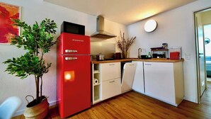 A compact kitchen with a red refrigerator, white cabinets, and a wooden countertop. - Modernes Apartment direkt im Szeneviertel Kölns (Köln)