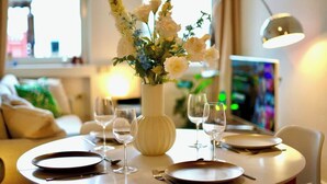 A dining table set with plates, cutlery, and wine glasses, with a vase of flowers in the center. - Modernes Apartment direkt im Szeneviertel Kölns (Köln)
