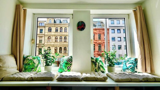 A room with a window seat, potted plants, and a view of historic buildings. - Modernes Apartment direkt im Szeneviertel Kölns (Köln)