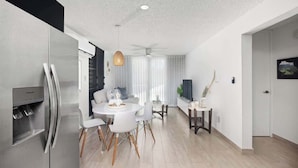 Eine moderne Küche mit Einbaukühlschrank, einem Essbereich mit rundem Tisch und weißen Stühlen sowie einem Deckenventilator.