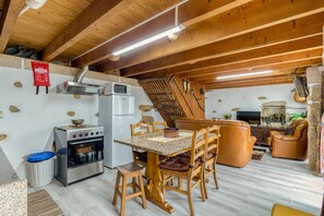 A rustic kitchen with a stove, oven, and microwave, wooden chairs, a dining table, and a stone wall. - Apartment 'Casa Alto Das Fragas' with Mountain View, Wi-Fi and Air Conditioning (Canedo de Basto)