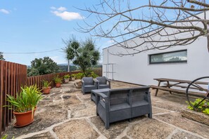 A patio area with wicker furniture, potted plants, and a wooden fence. - Apartment 'Casa Alto Das Fragas' with Mountain View, Wi-Fi and Air Conditioning (Canedo de Basto)
