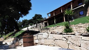Un mur de soutènement en pierre, une porte en bois et un bâtiment doté d’un balcon.