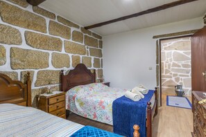 Ein Schlafzimmer mit einer Steinsäule, einem hölzernen Bett mit floralem Bettbezug, einem Nachttisch mit Lampe und einem Holzschrank.