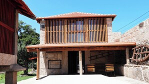 Un bâtiment à deux étages, avec un toit en tuiles, des lambris en bois à l’étage supérieur et un mur en pierre sur le côté droit.