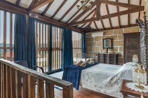 A room with a bed, a dresser, a mirror, and a window with curtains.