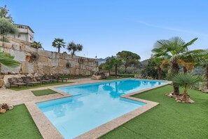 Ein Swimmingpool mit einer Steinmauer und Palmen im Hintergrund.