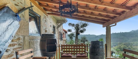 A rustic outdoor seating area with stone walls, wooden furniture, and large barrels.