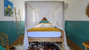 A room with a bed under a white canopy, a wooden ladder, a cowhide rug, and a painting on the wall.